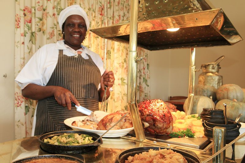 A chef in whites carving a roast at the carvery station