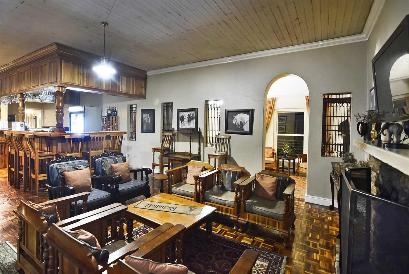 Lounge armchairs around a low table with horse paintings on the wall and a fireplace