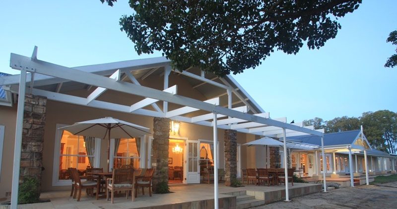 The main building at twilight, its pergola and dining tables lit from within