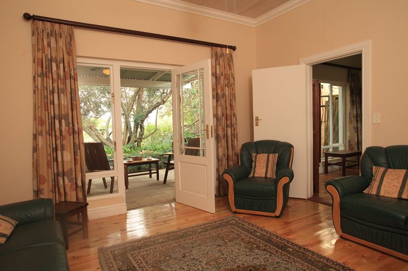 A guest lounge with dark green leather sofas opening onto the patio