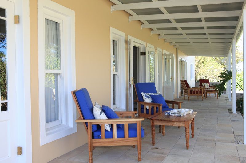 The Manor veranda lined with blue-cushioned wooden armchairs and low tables