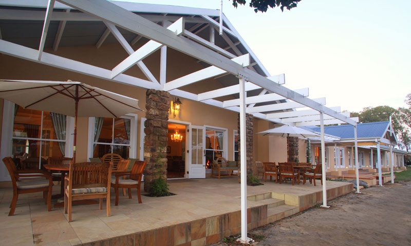 A covered pergola walkway with dining tables running along the building