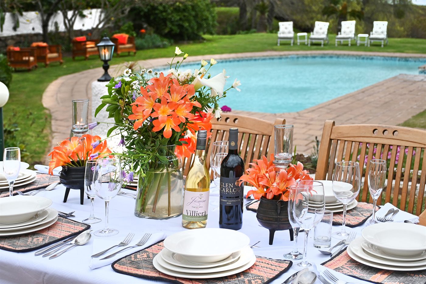 A table laid with wine and flowers on the lawn beside the pool