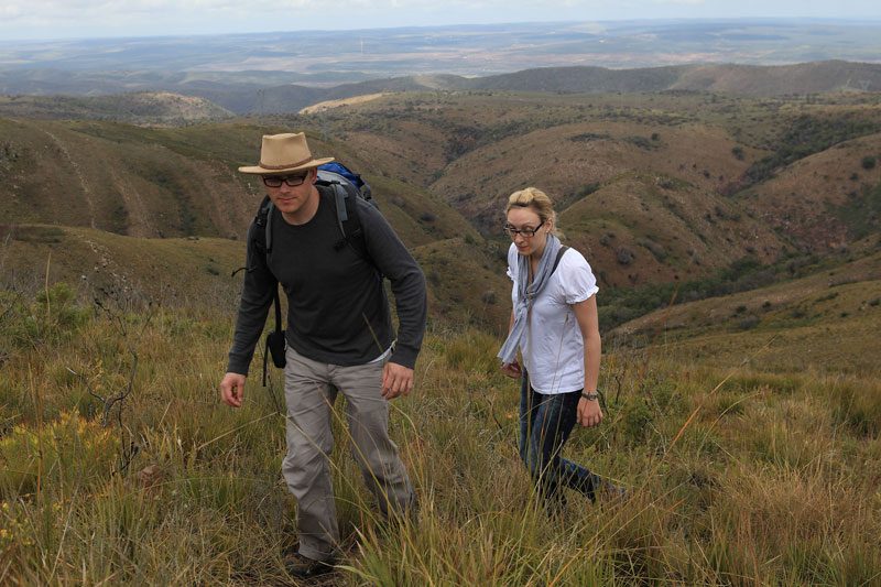 Two walkers climbing a grassy ridge on the Porcupine Trail above the valley