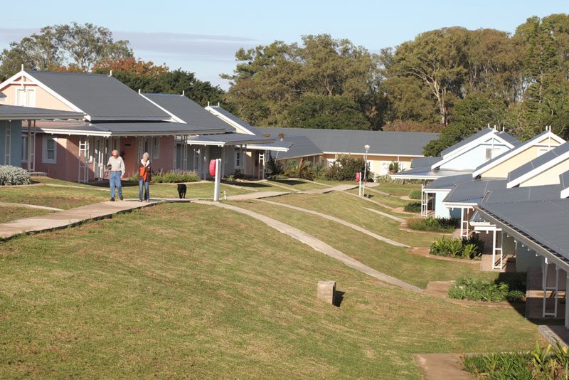 A row of Village cottages with gabled roofs along a sloping lawn