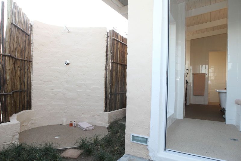 A private outdoor shower screened by reed walls, opening off the bathroom