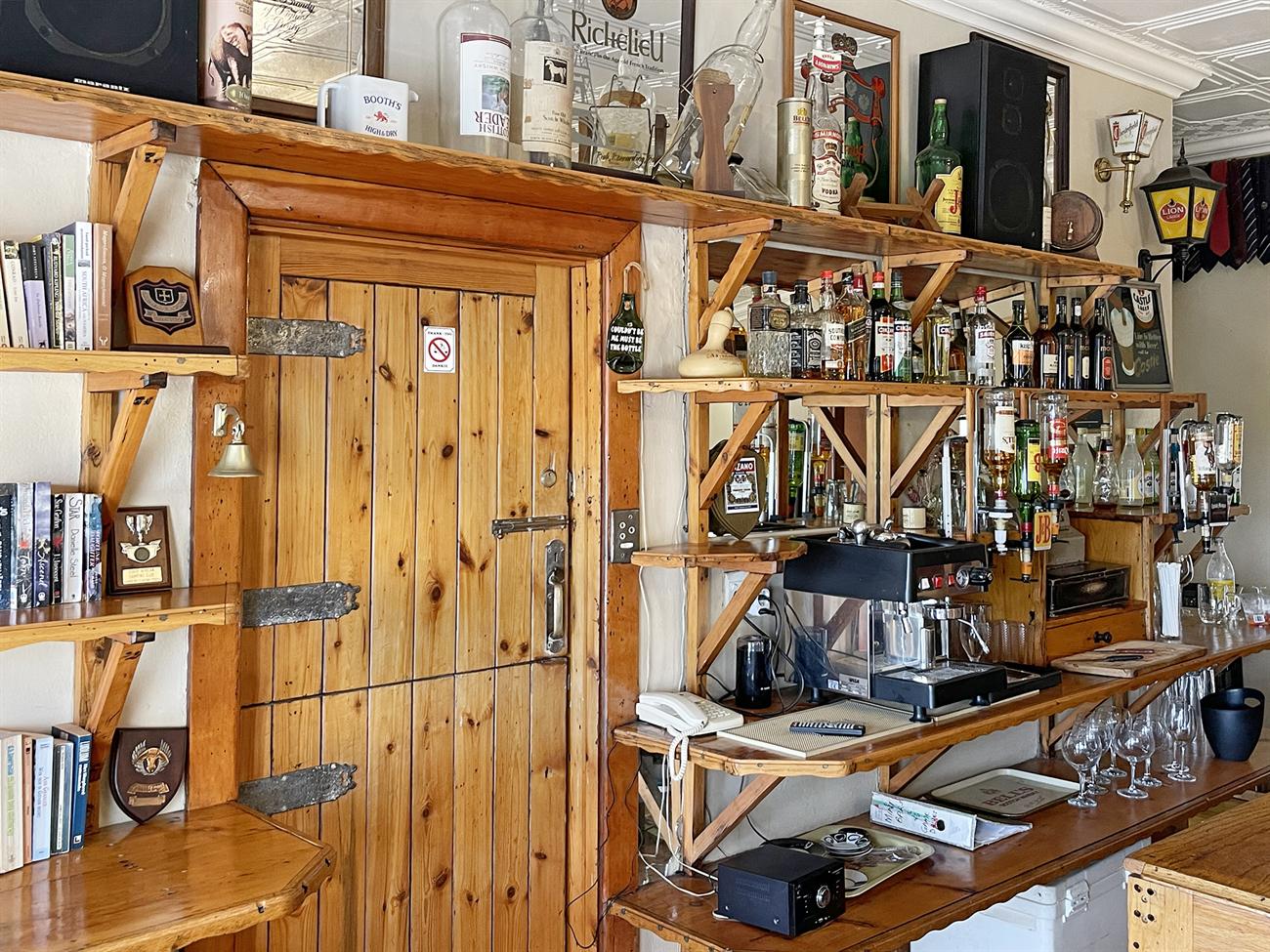 The back bar at Woodifields, its pine shelves crowded with bottles, books and sporting trophies