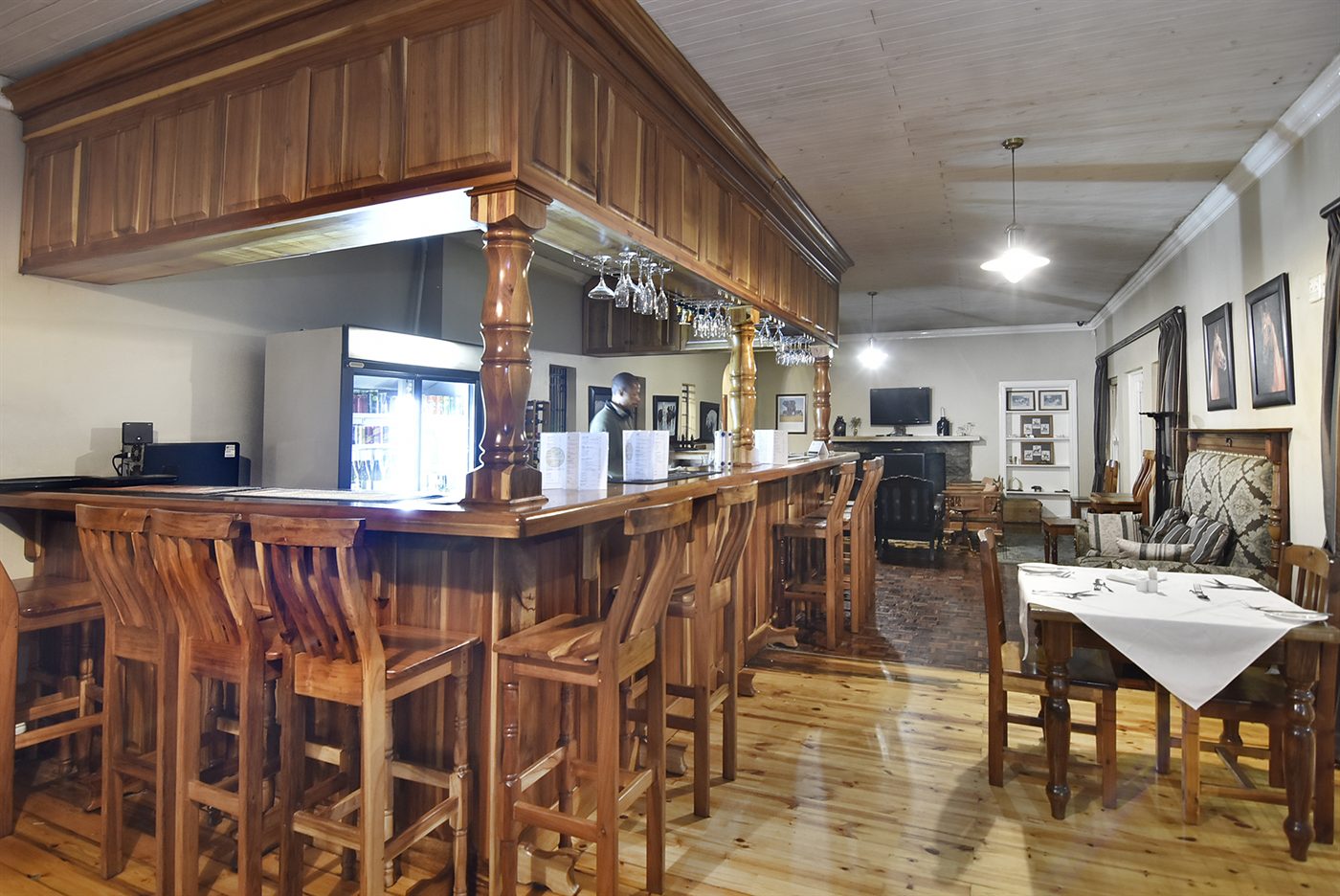 The long timber bar counter at Woodifields with turned pillars, bar stools and the dining room beyond